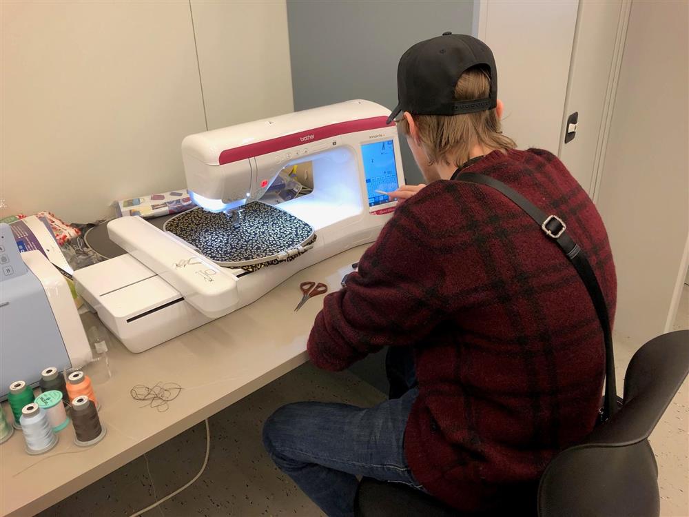 Elev som arbeider med broderingsmaskin - Klikk for stort bilete